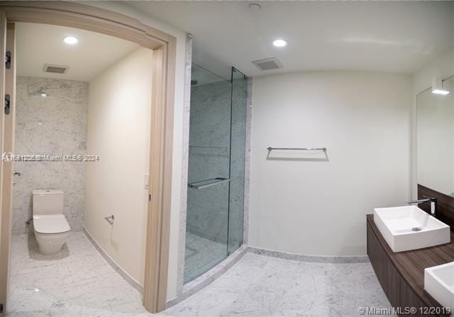 bathroom with walk in shower, vanity, and toilet