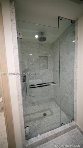 bathroom with a shower with door and toilet