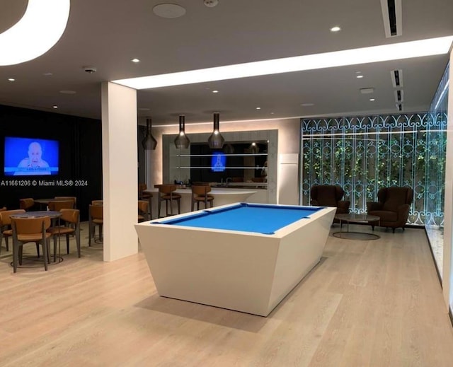 game room with pool table, light hardwood / wood-style floors, expansive windows, and bar