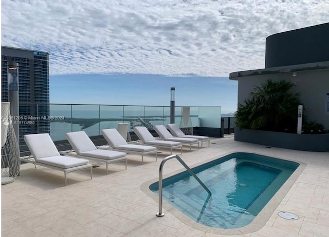 view of pool with a patio and a water view