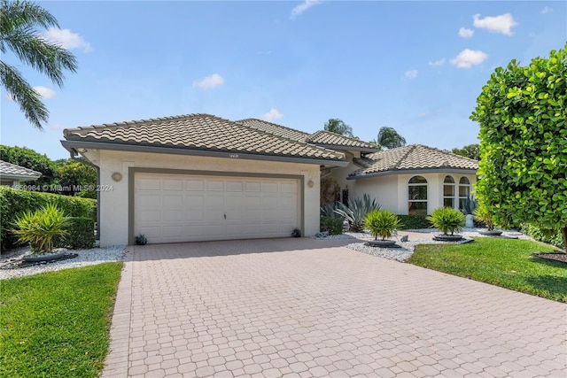 mediterranean / spanish house featuring a garage and a front yard