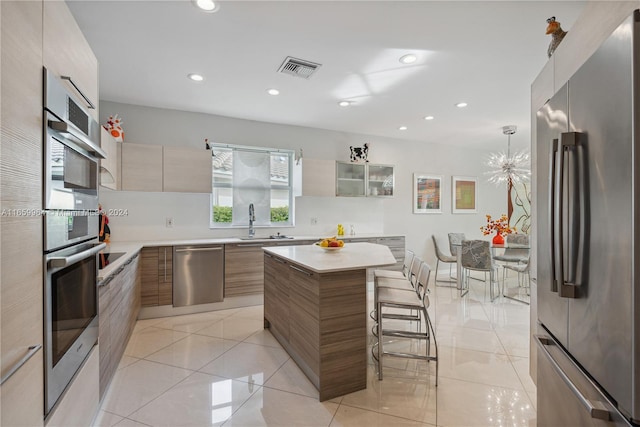 kitchen featuring a center island, sink, a kitchen bar, appliances with stainless steel finishes, and decorative light fixtures