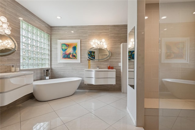 bathroom with tile walls, tile patterned floors, a bath, and vanity