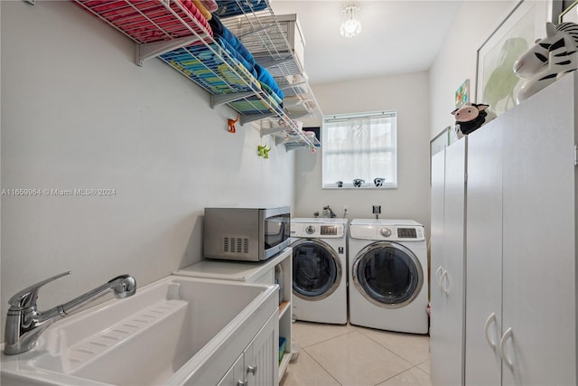 clothes washing area with cabinets, light tile patterned floors, washer and dryer, and sink