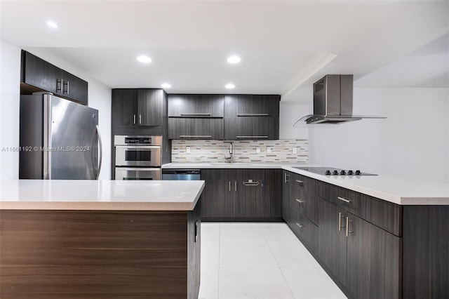 kitchen featuring light tile patterned flooring, sink, wall chimney range hood, decorative backsplash, and appliances with stainless steel finishes