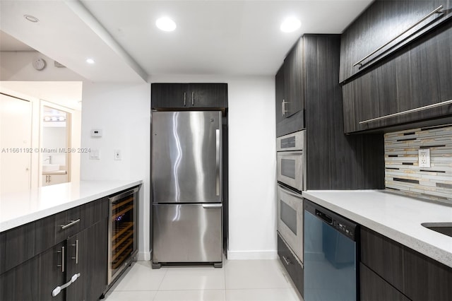 kitchen with beverage cooler, backsplash, appliances with stainless steel finishes, and light tile patterned floors