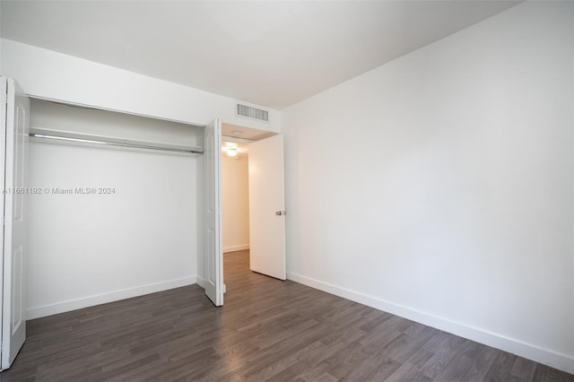 unfurnished bedroom with a closet and dark hardwood / wood-style floors