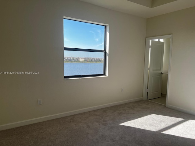 carpeted spare room featuring a water view