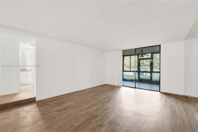 spare room featuring floor to ceiling windows, wood-type flooring, and ceiling fan