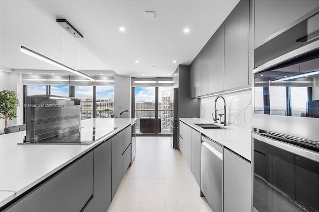 kitchen with gray cabinetry, sink, light tile patterned floors, decorative light fixtures, and stainless steel appliances