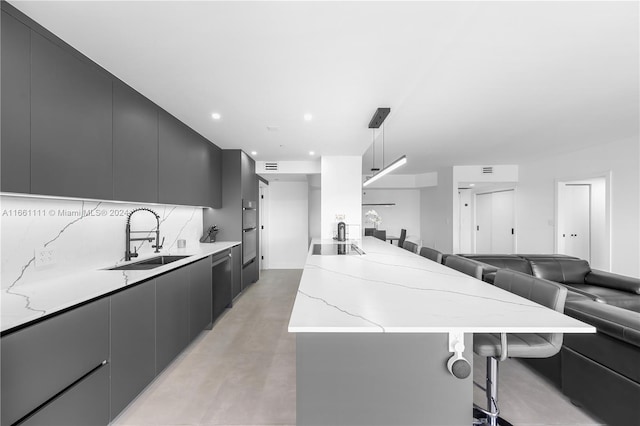 kitchen with sink, a breakfast bar area, tasteful backsplash, decorative light fixtures, and stainless steel appliances