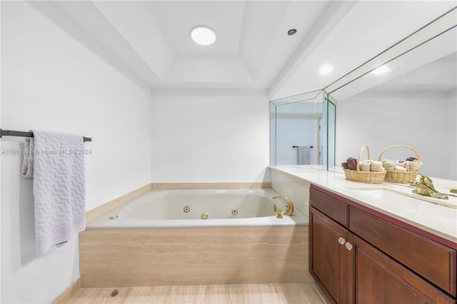 bathroom featuring vanity, tiled bath, and a raised ceiling