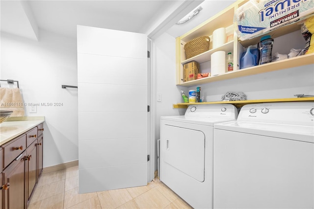 laundry area with cabinets, light tile patterned floors, and washer and clothes dryer