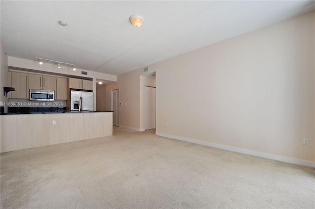 kitchen featuring light carpet, backsplash, rail lighting, stainless steel appliances, and light brown cabinetry