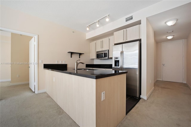 kitchen with appliances with stainless steel finishes, kitchen peninsula, sink, and light colored carpet