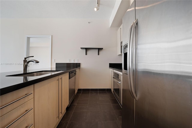 kitchen featuring dark tile patterned flooring, light brown cabinetry, appliances with stainless steel finishes, and sink