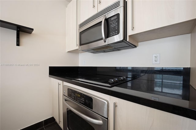 kitchen with dark tile patterned floors, stainless steel appliances, and white cabinets