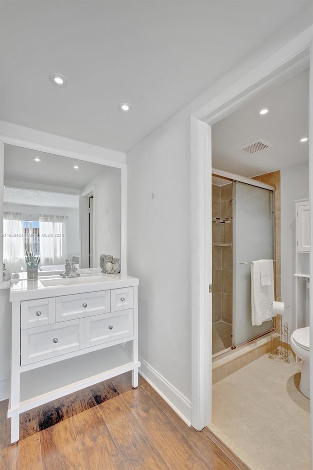 bathroom with an enclosed shower, hardwood / wood-style flooring, vanity, and toilet