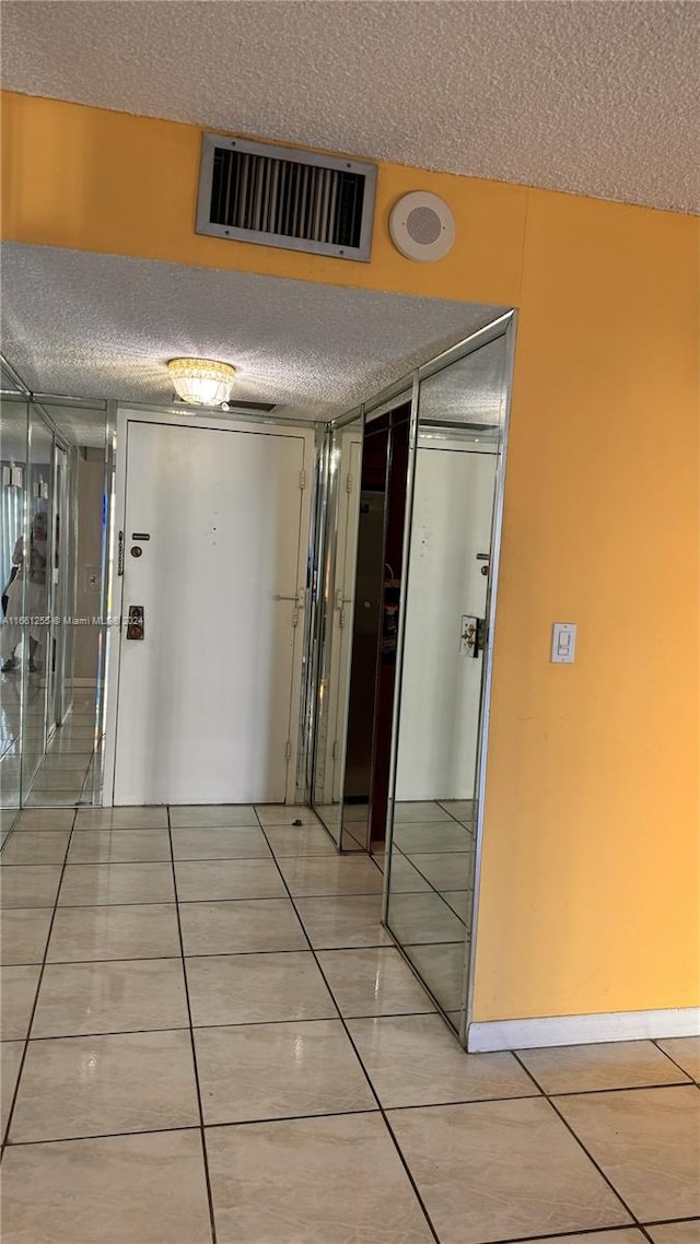 hallway featuring a textured ceiling and tile patterned floors