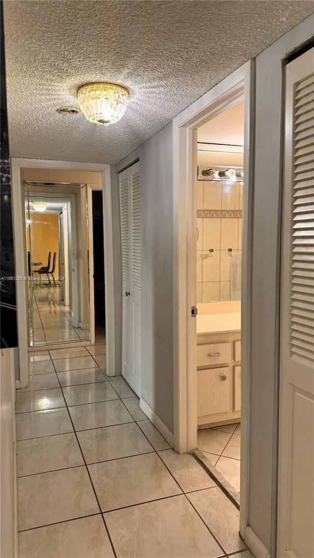 hallway featuring a textured ceiling and light tile patterned floors