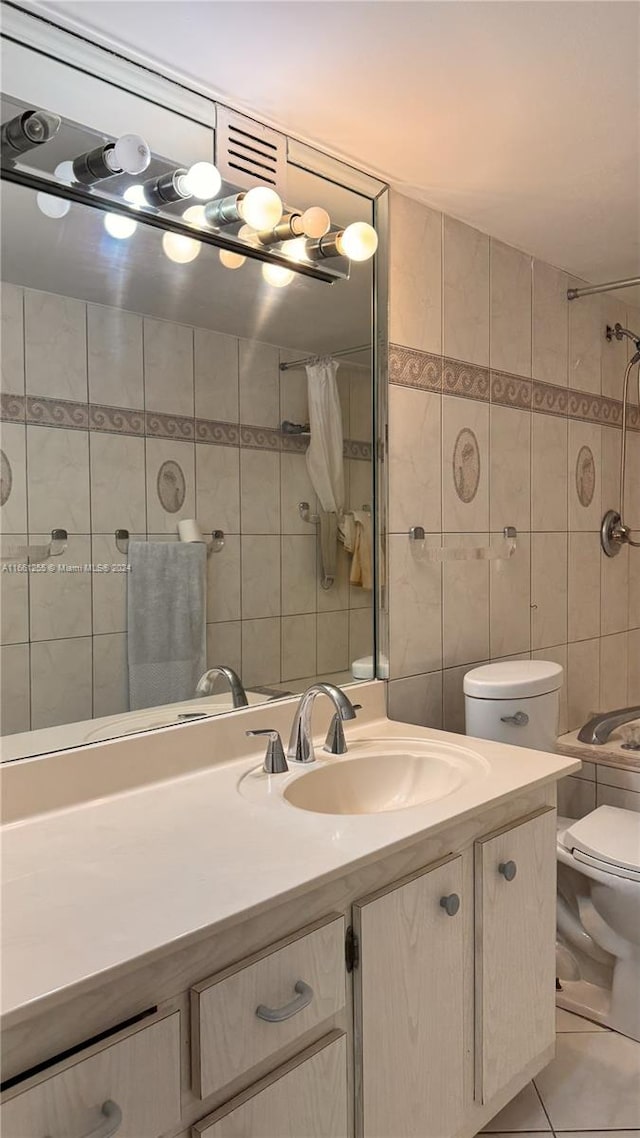 bathroom with tile walls, a shower with curtain, tile patterned floors, vanity, and toilet