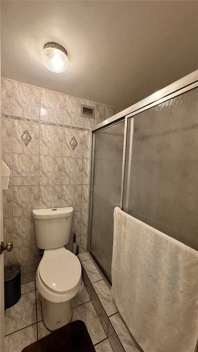 bathroom with walk in shower, tile walls, tile patterned flooring, and toilet