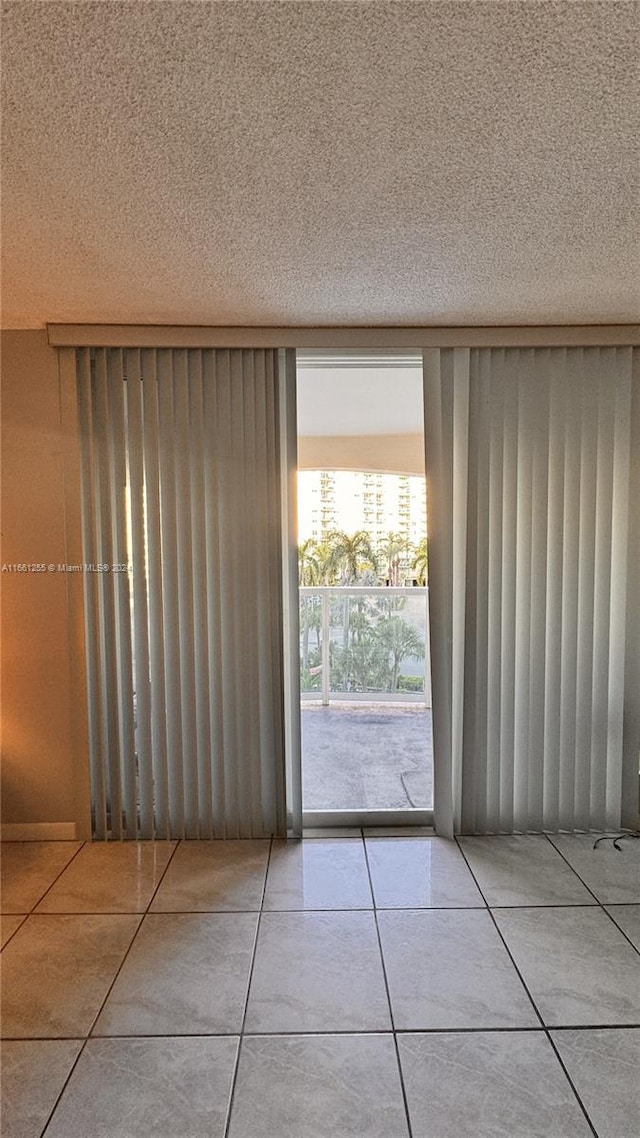 unfurnished room featuring a textured ceiling and light tile patterned floors