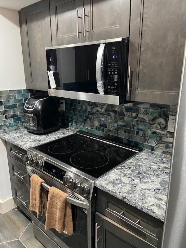 kitchen featuring light stone counters, light tile patterned flooring, stainless steel appliances, and backsplash