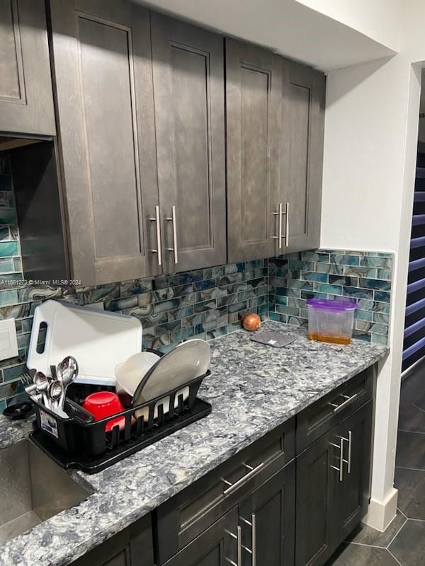 kitchen with dark brown cabinetry, light stone countertops, and decorative backsplash