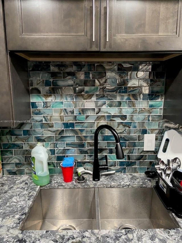 details with dark brown cabinets, backsplash, sink, and stone countertops