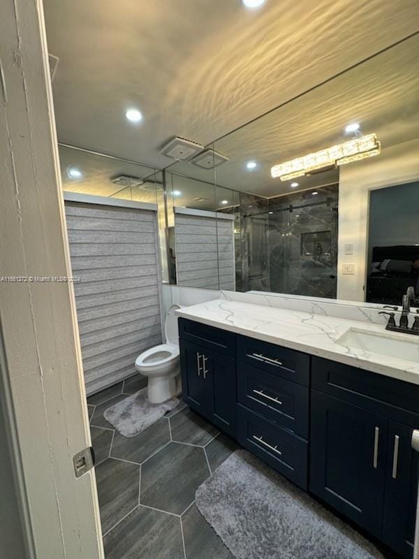 bathroom with tile patterned flooring, a shower with door, vanity, and toilet