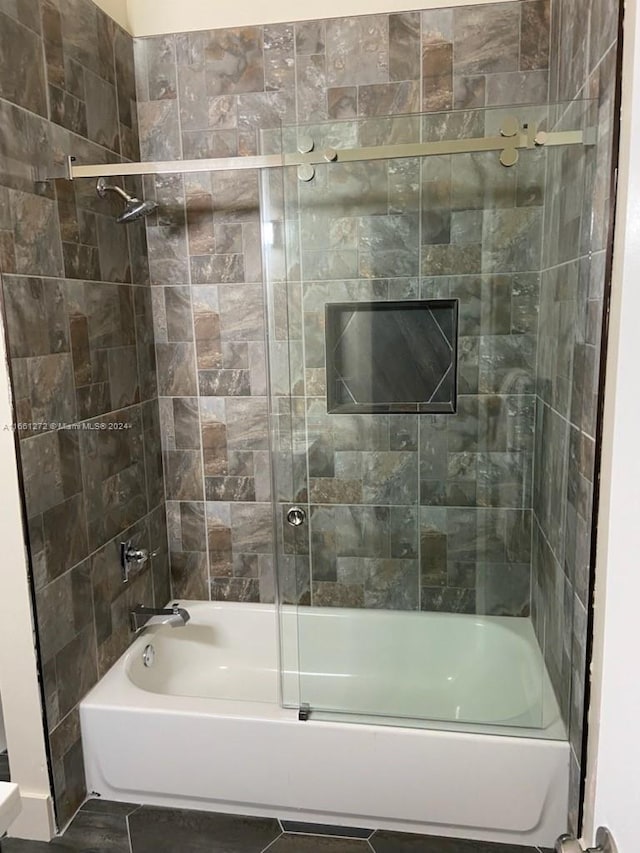 bathroom featuring tile patterned flooring and shower / bath combination with glass door