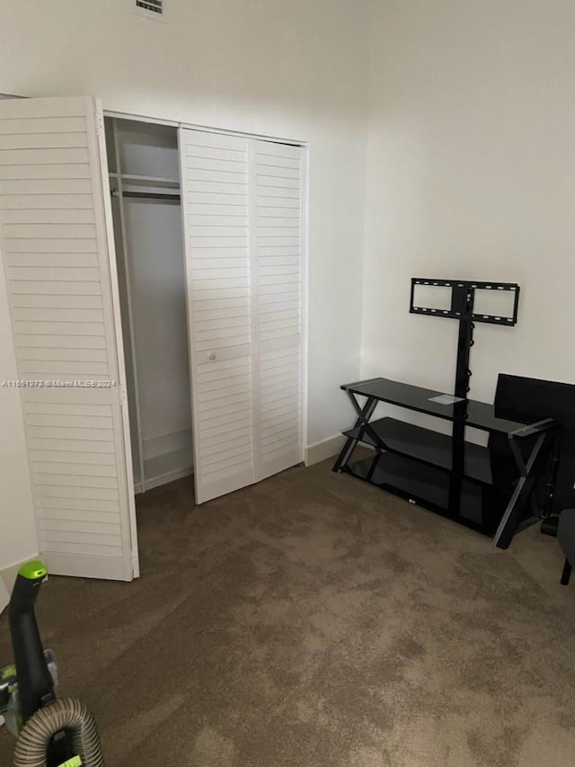 bedroom with dark colored carpet and a closet