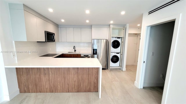 kitchen with kitchen peninsula, stainless steel appliances, and stacked washer and clothes dryer