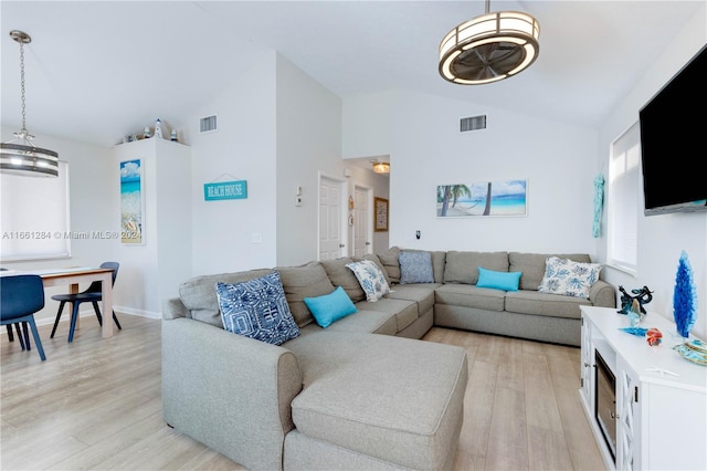 living room with a notable chandelier, lofted ceiling, and light hardwood / wood-style floors