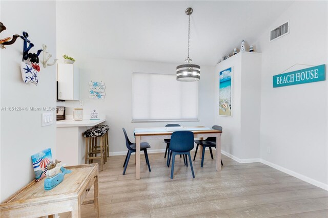 dining room with lofted ceiling, a chandelier, and light hardwood / wood-style flooring