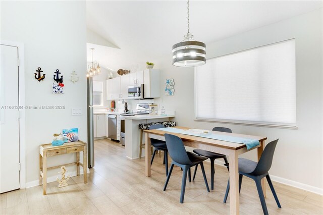 dining space featuring light hardwood / wood-style flooring, vaulted ceiling, plenty of natural light, and sink