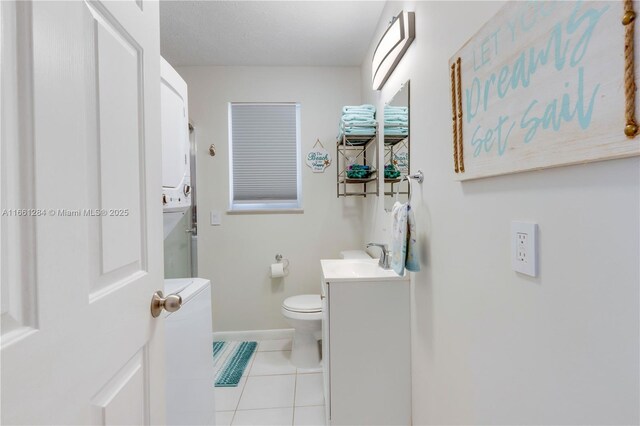 bathroom with stacked washer / drying machine, an enclosed shower, tile patterned floors, vanity, and toilet