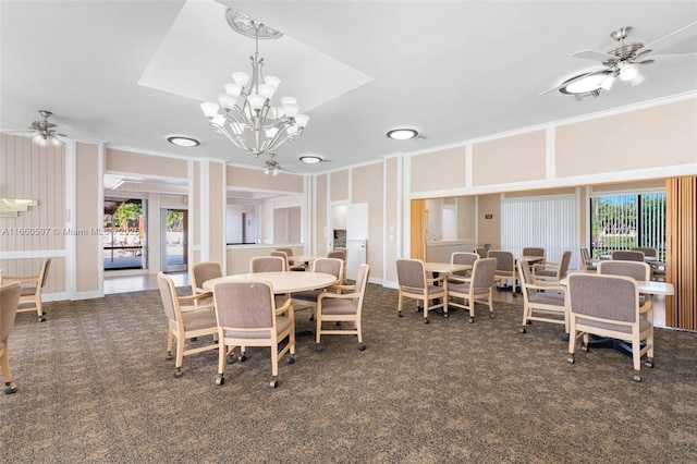 carpeted dining space featuring ceiling fan with notable chandelier and crown molding