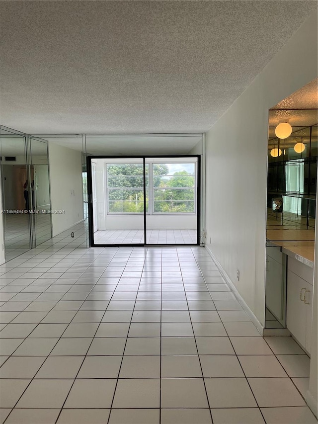 unfurnished room with a textured ceiling and light tile patterned floors