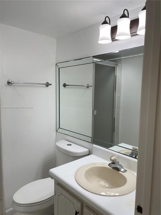 bathroom with vanity, toilet, and a shower with door