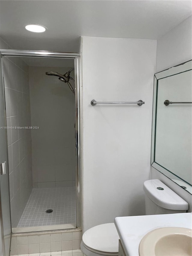 bathroom featuring a shower with door, toilet, tile patterned floors, and vanity