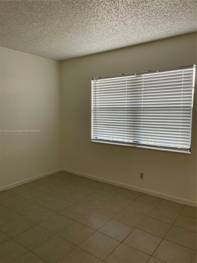 tiled empty room with a textured ceiling