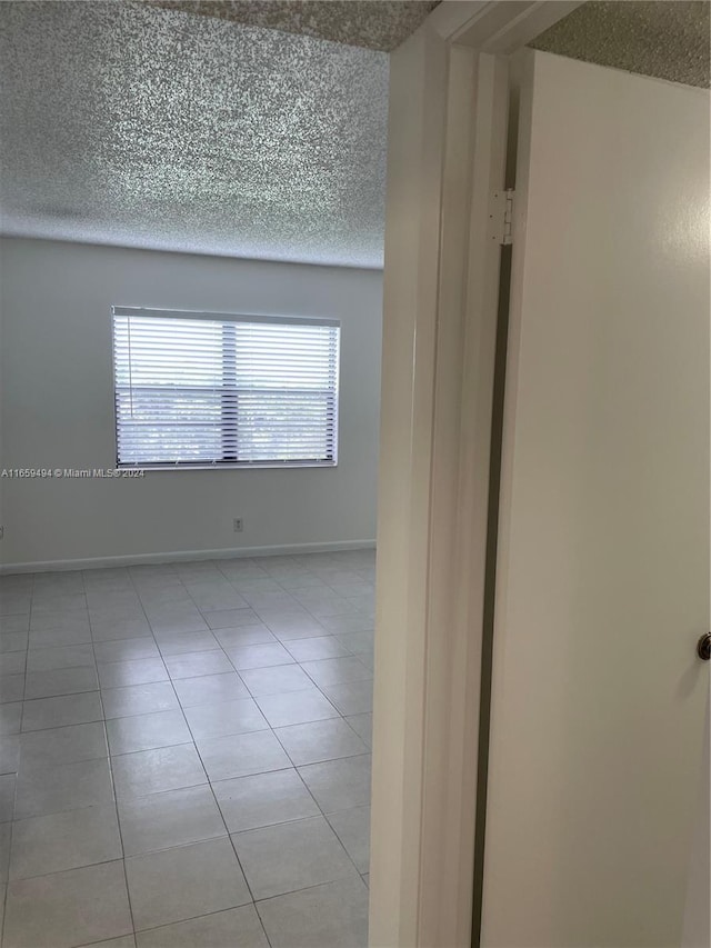 unfurnished room with a textured ceiling and light tile patterned floors