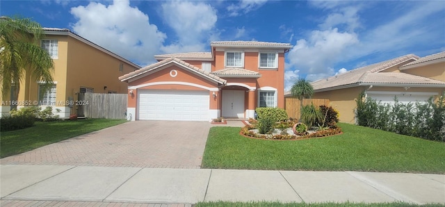 mediterranean / spanish home featuring a front yard, an attached garage, stucco siding, a tile roof, and decorative driveway