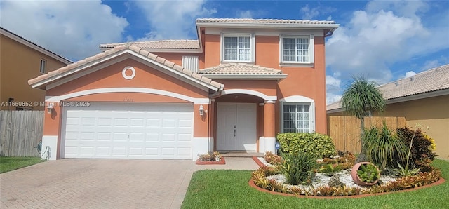 mediterranean / spanish-style home with stucco siding, a tile roof, decorative driveway, and fence