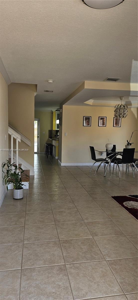 hallway with light tile patterned floors, baseboards, and a textured ceiling