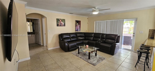 living room with light tile patterned floors, arched walkways, crown molding, and a ceiling fan