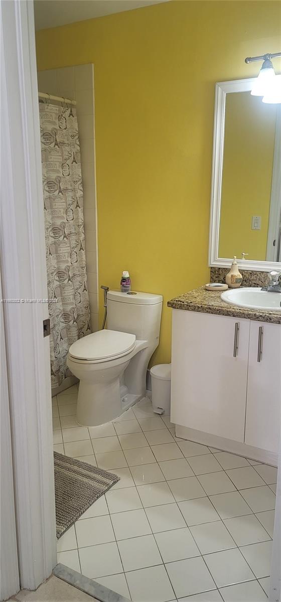 bathroom with a shower with curtain, vanity, tile patterned flooring, and toilet