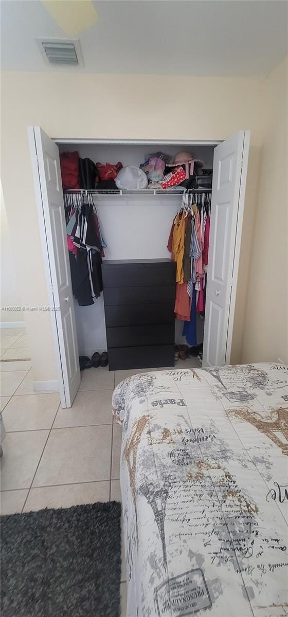 bedroom with light tile patterned floors, visible vents, and a closet